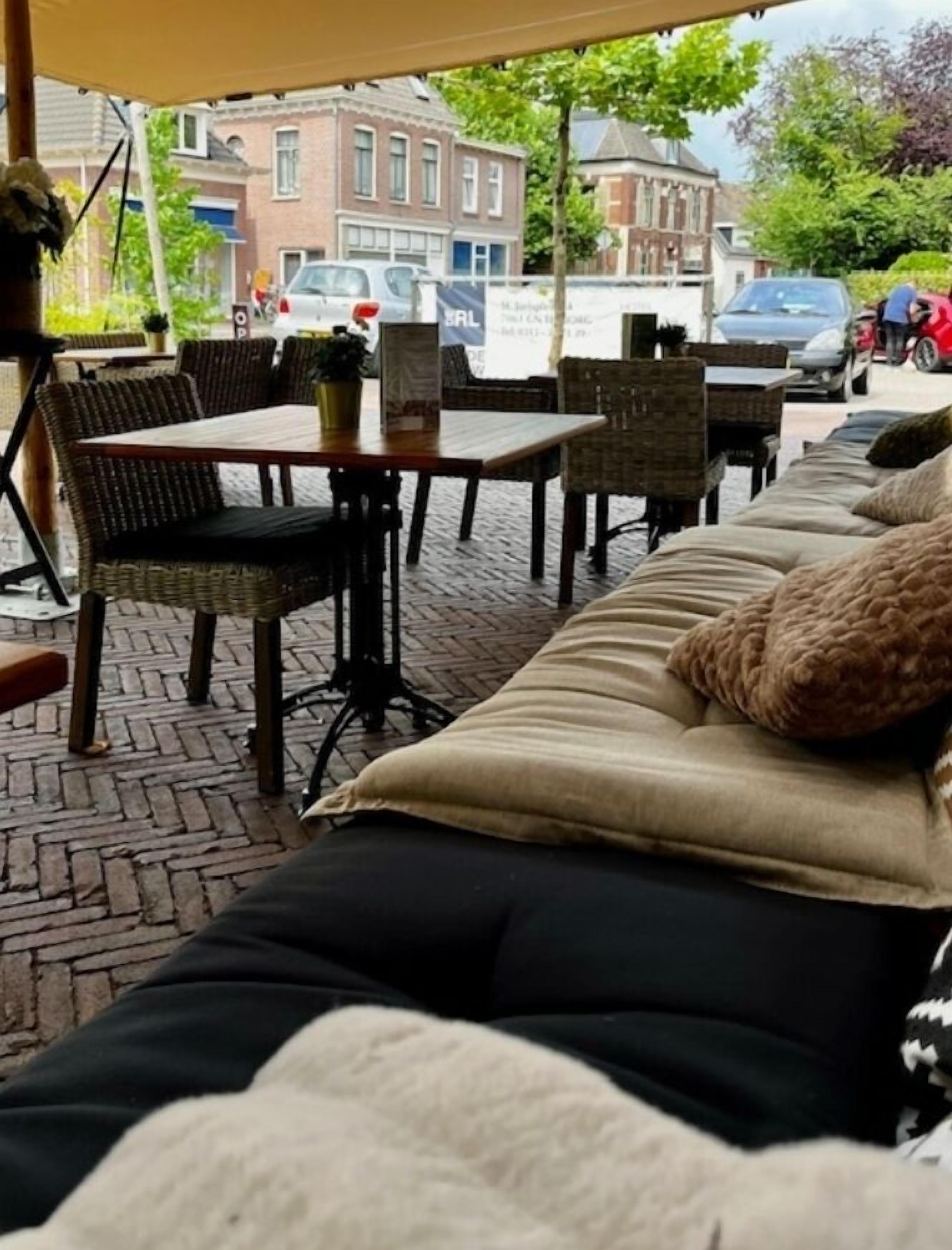 An outdoor seating area with wicker furniture, a table, and a sofa with cushions.