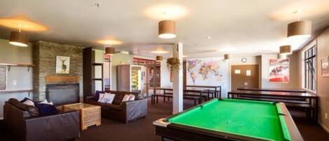 A pool table in a room with a fireplace, sofas, and a map on the wall.