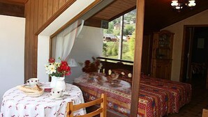 A cozy bedroom with a large bed, a wooden headboard, and a window with curtains.