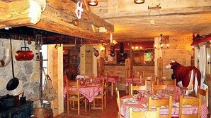 A rustic wooden interior with tables set for dining, a cow statue, and various hanging lights.