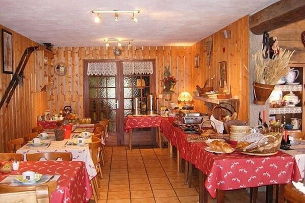 Un comedor rústico con paredes de madera y mesas cubiertas con manteles rojos.