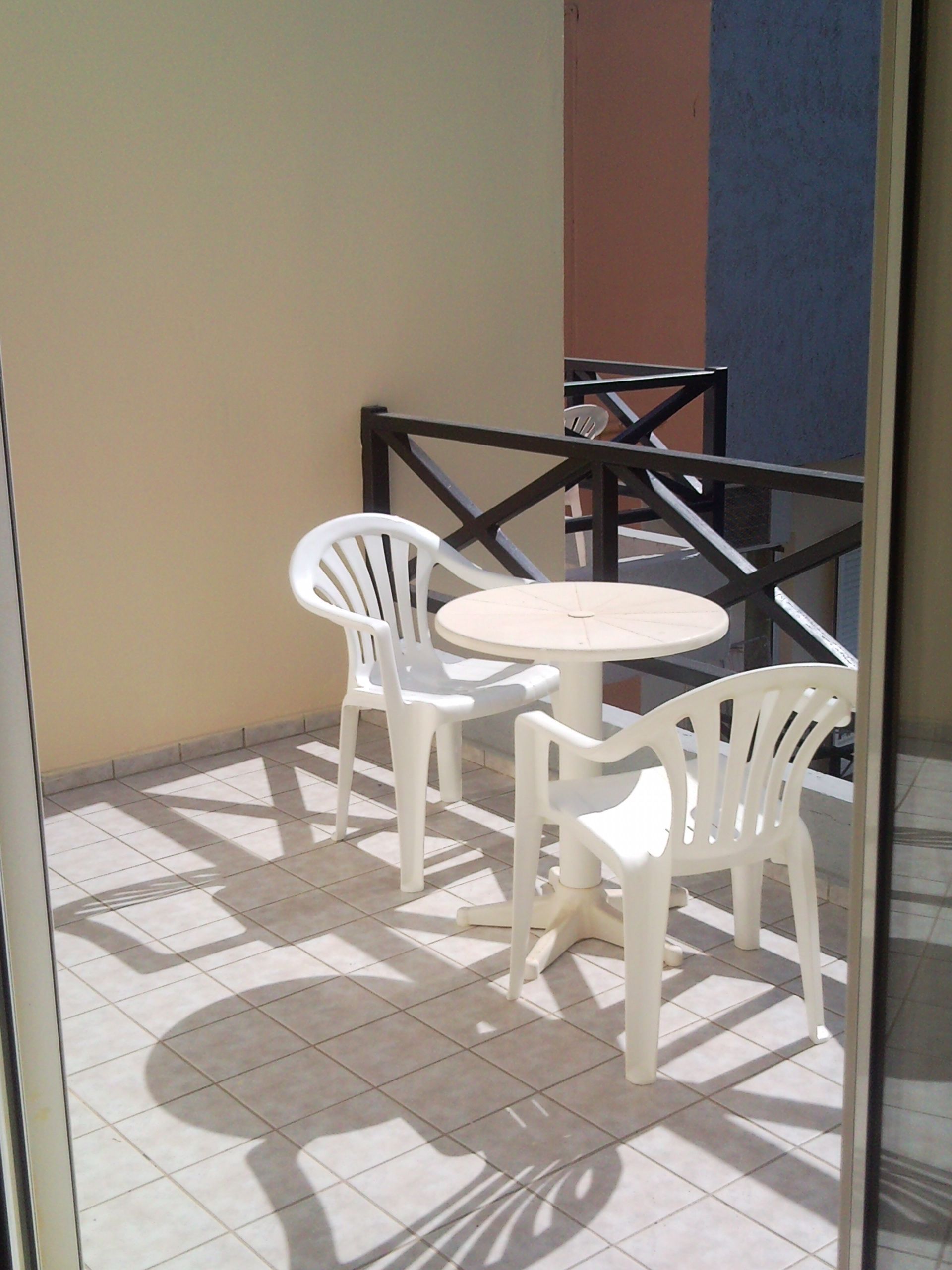 A small outdoor patio area with a round table and four white plastic chairs.