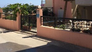 A residential building with a gated entrance, a sign indicating 'Stella' rooms, and a tree in front. - Stella Apartments (Hersonissos)