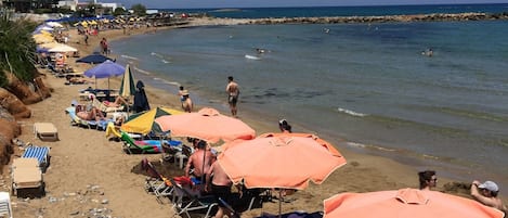 På stranden, solstolar, parasoller och volleyboll