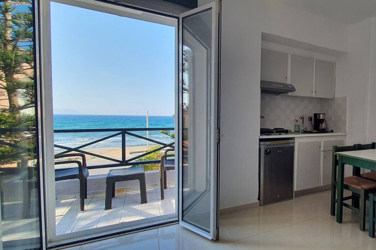 A kitchen with a view of the sea, a dining area with chairs, and a small table.