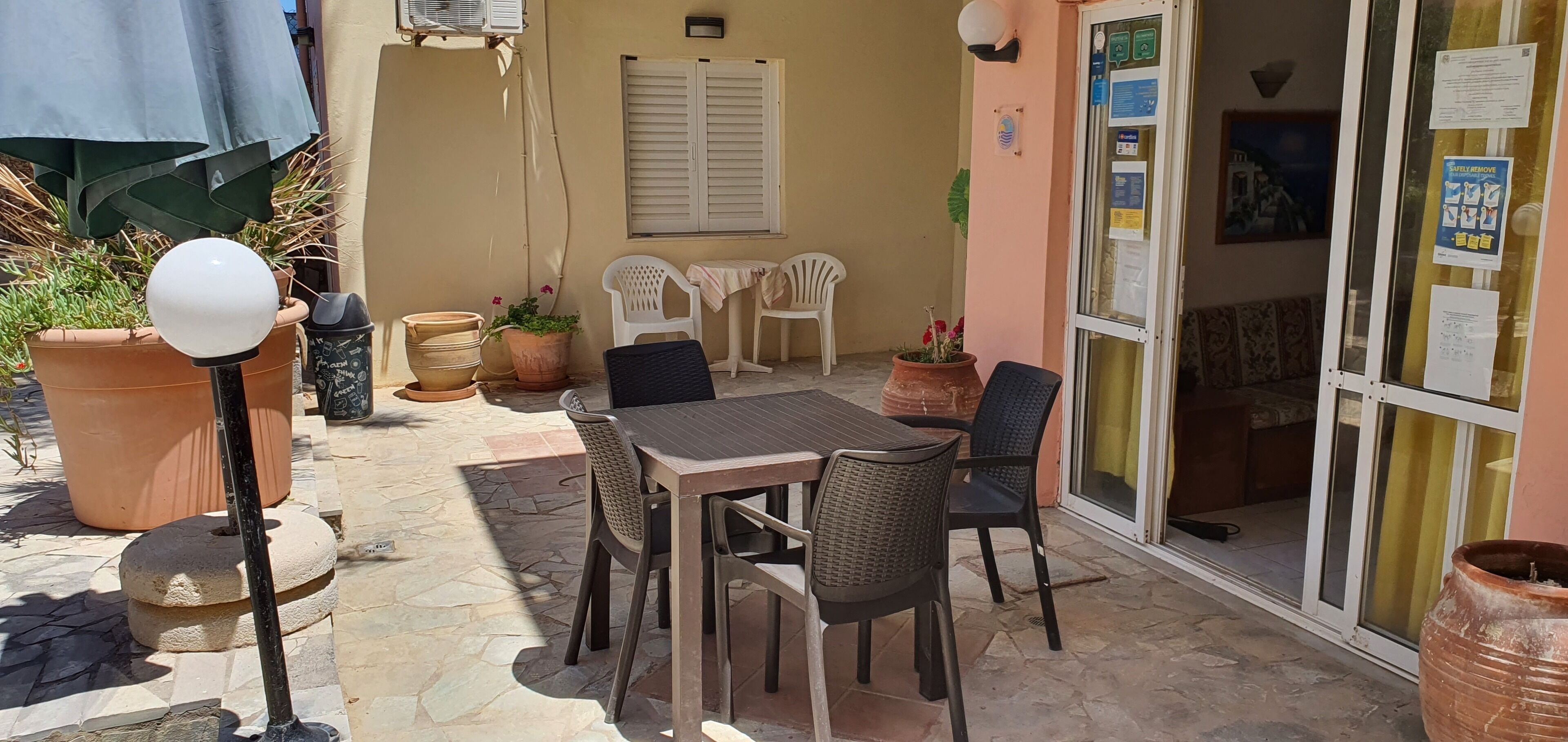 Eine Terrasse im Freien mit Tisch, Stühlen, Blumentöpfen und einer Lampe.