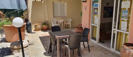 Eine Terrasse im Freien mit Tisch, Stühlen, Blumentöpfen und einer Lampe.