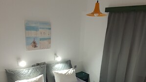 A neatly made bed with a purple bedspread, two pillows, and two towels folded on the bed. - Stella Apartments (Hersonissos)