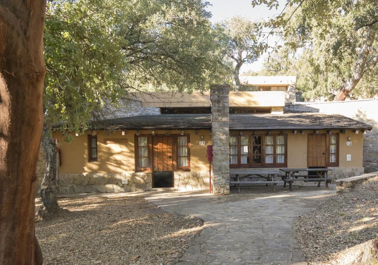 A rustic building with a stone facade, wooden doors, and a bench outside.