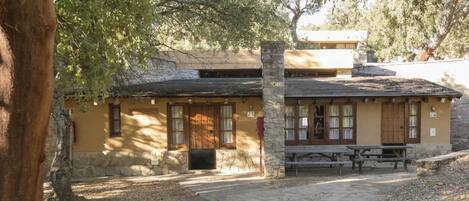 A rustic building with a stone facade, wooden doors, and a bench outside.