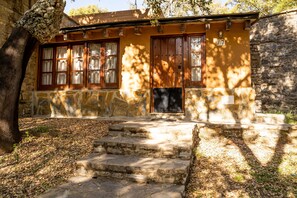 A stone building with wooden windows and a door, surrounded by trees and a stone wall. - Albergue Inturjoven Cortes de la Frontera - Hostel (Cortes de la Frontera)