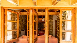 Una habitación con pared de piedra, vigas de madera y un amplio ventanal con vistas.