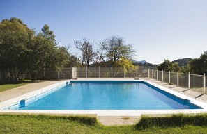 A rectangular swimming pool with a white border, surrounded by a grassy area and a fence. - Albergue Inturjoven Cortes de la Frontera - Hostel (Cortes de la Frontera)