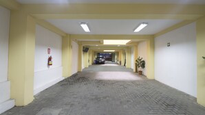 A corridor with yellow walls, a fire extinguisher, and a potted plant. - Hotel Alexander (Trujillo)