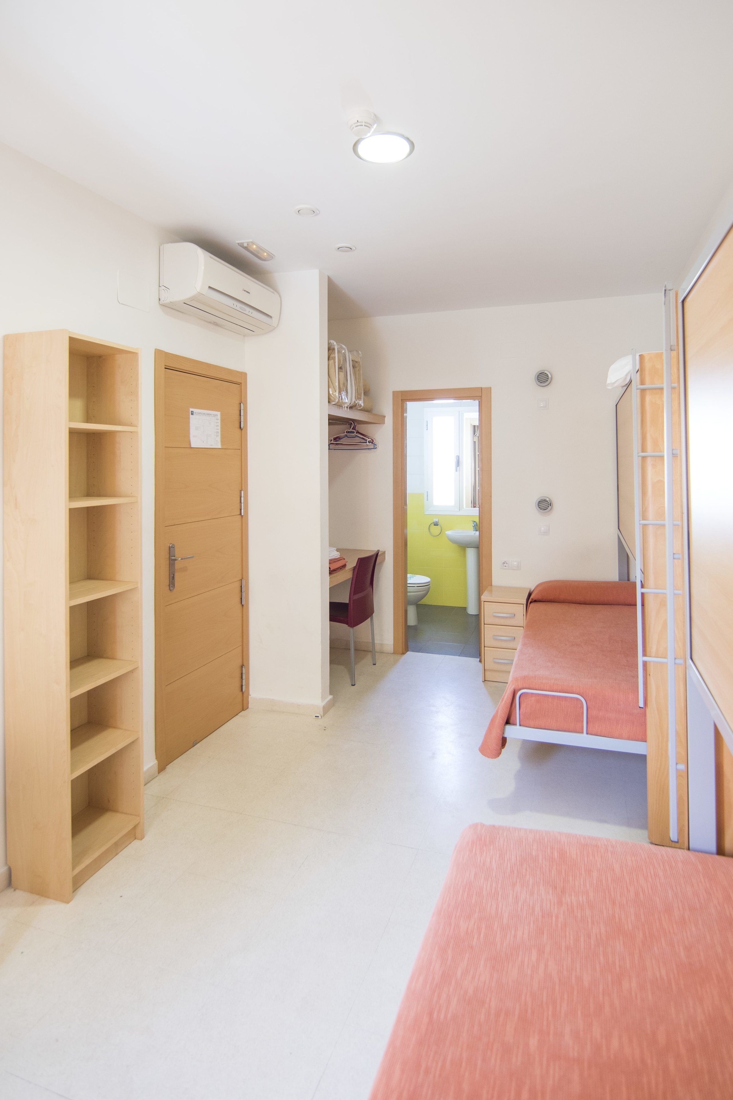A room with a bed, a wardrobe, a desk, and a bathroom.