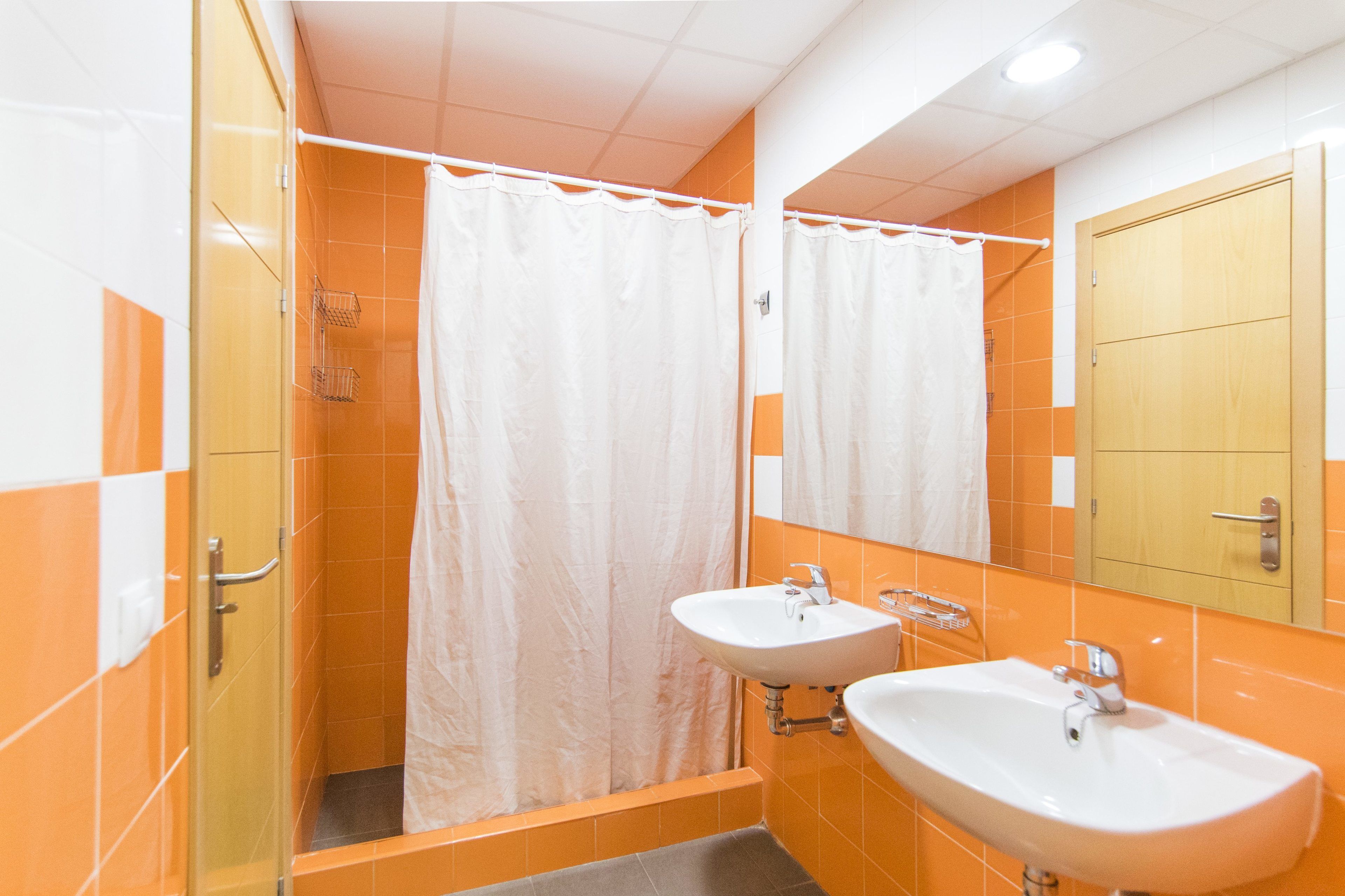 Un baño con dos lavamanos, ducha y espejo.