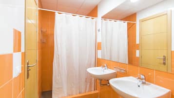 Un baño con dos lavamanos, ducha y espejo.
