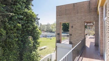 Un edificio de ladrillo con un balcón que da a una zona verde y un puente.