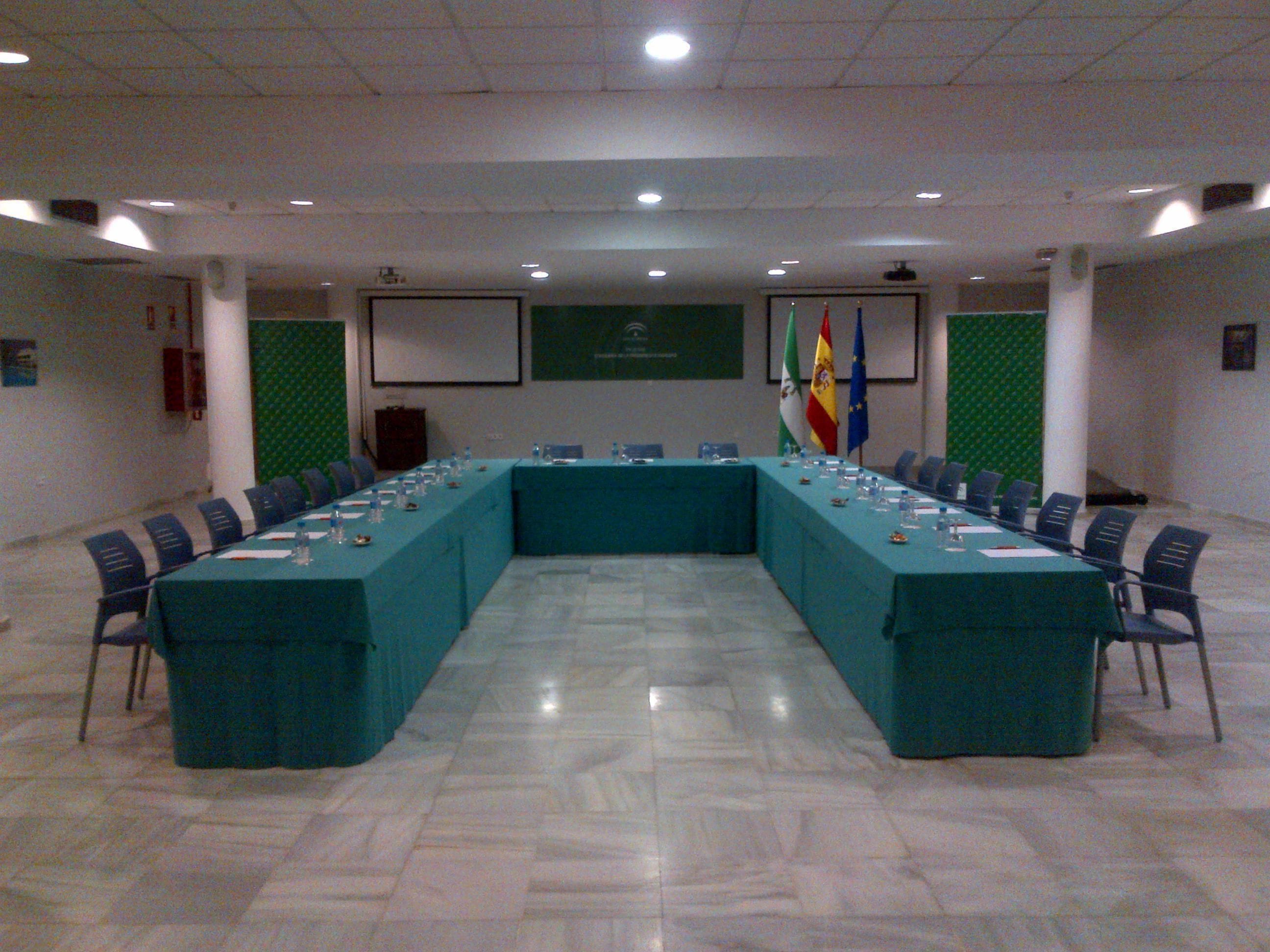 Uma sala de conferência com uma mesa comprida, cadeiras e bandeiras.