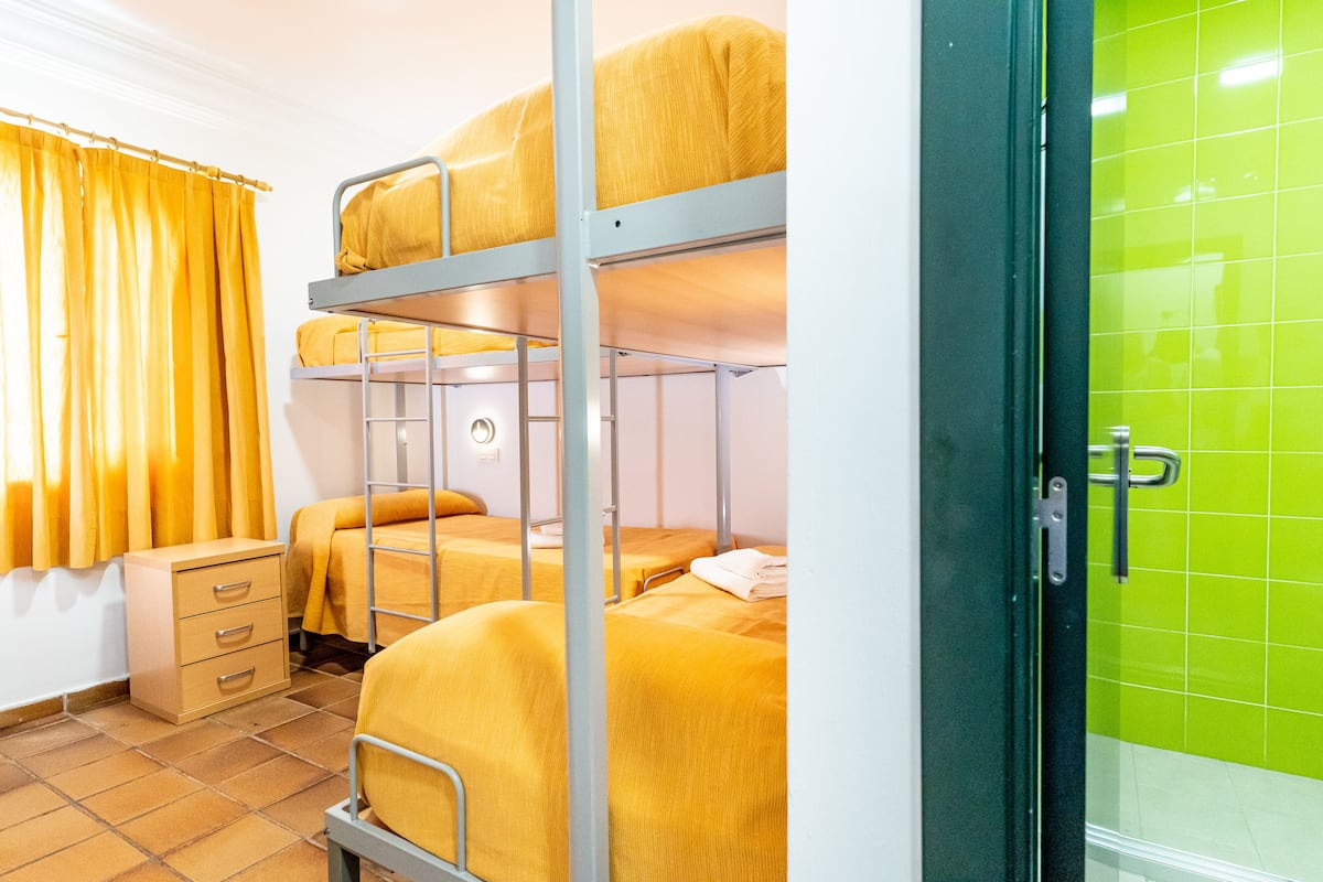 A bunk bed room with a green wall and a window with yellow curtains.