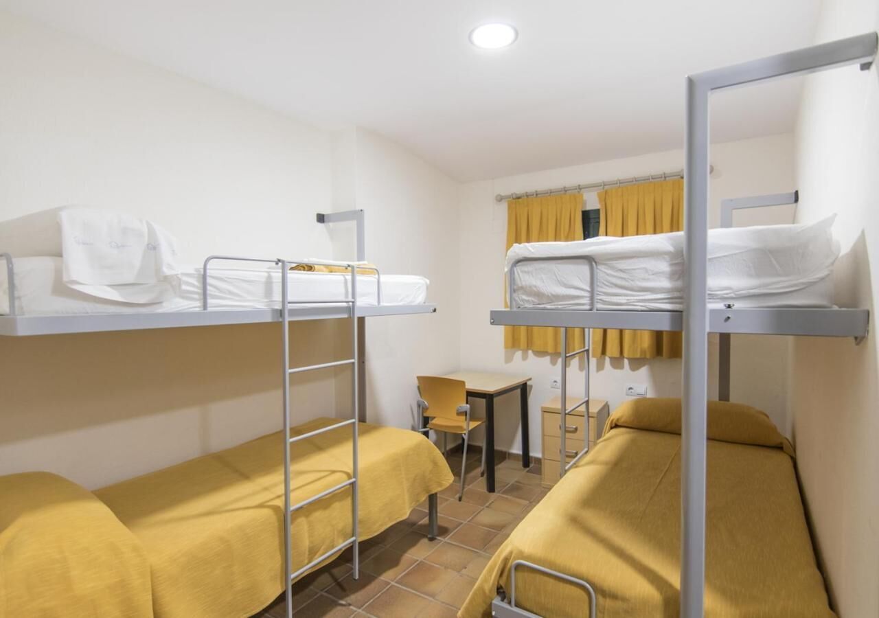Un dormitorio con literas, un escritorio y una silla.
