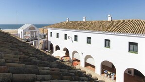 Un edificio bianco con diverse arcate e un tetto in tegole, vicino a una scala che conduce a una spiaggia.