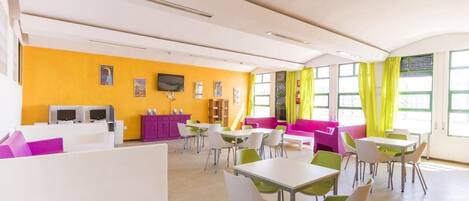 A bright, modern room with yellow walls, white furniture, and large windows with green curtains.