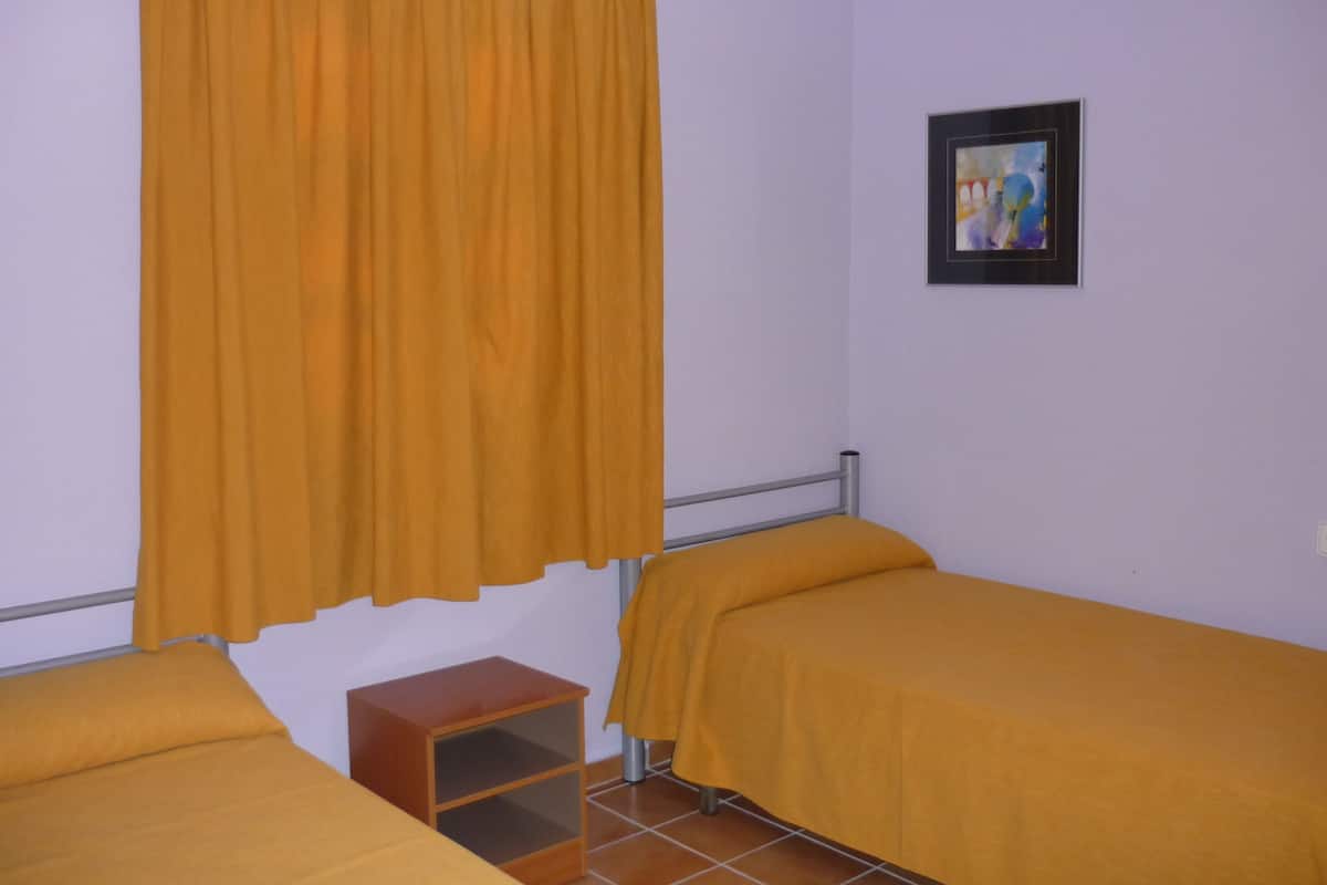 A room with two beds, a small wooden nightstand, and a painting on the wall.