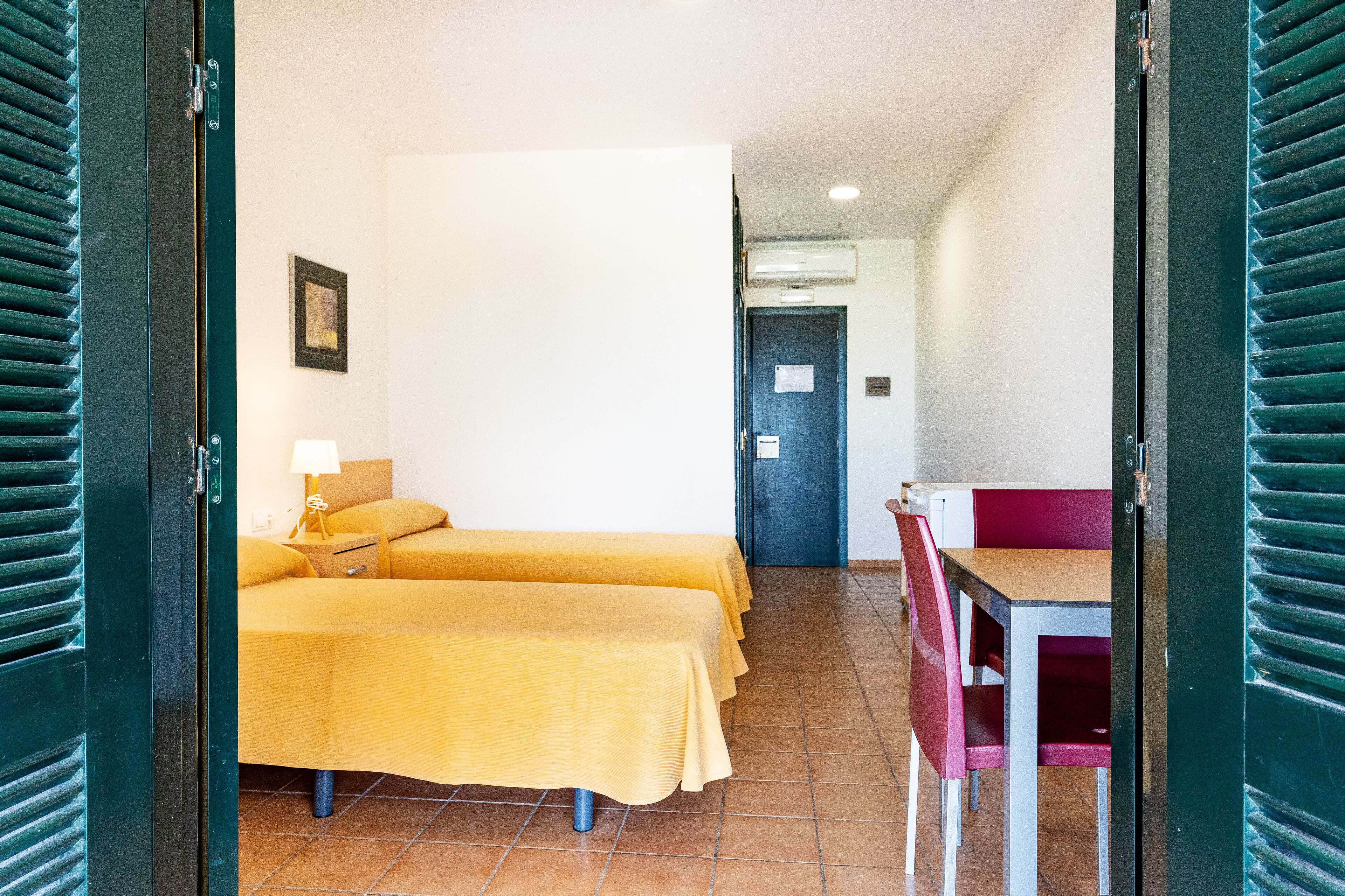 Habitación de hotel con dos camas, un escritorio y una silla.