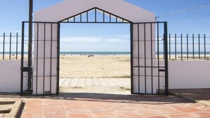 Un accesso recintato verso una spiaggia, con vista libera su spiaggia e mare.