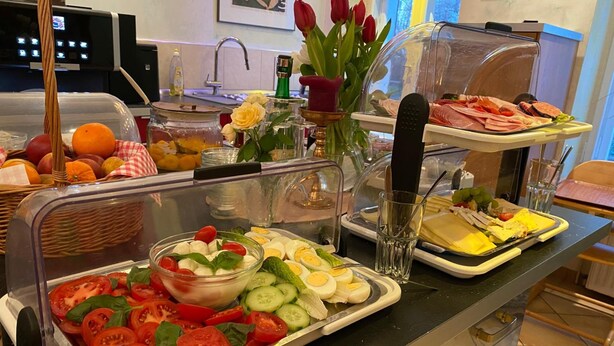 Un bufé con diversos alimentos, como tomates en rodajas, pepinos, huevos y carnes.