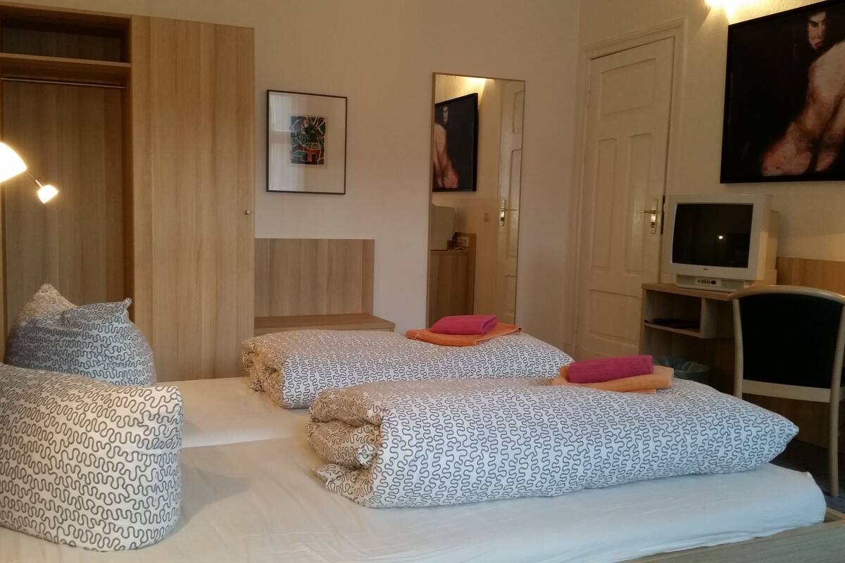 Habitación de hotel con dos camas, televisión y escritorio.
