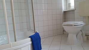Un baño con bañera, inodoro y cabina de ducha de vidrio.