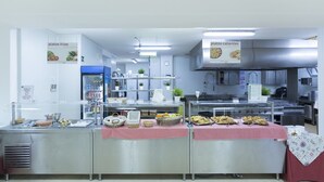 Een buffetopstelling met diverse gerechten en een keuken in de achtergrond.