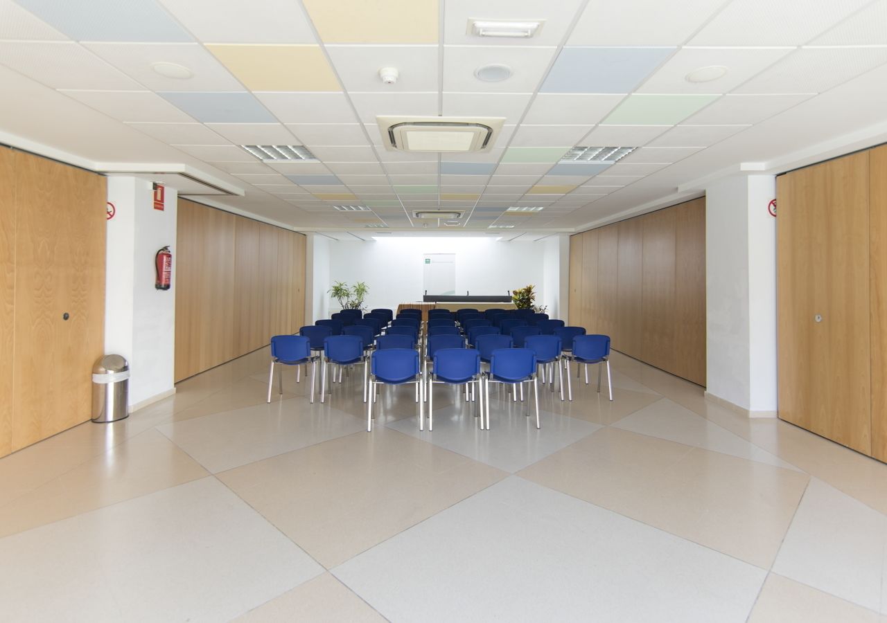 Une salle de conférence avec une longue table et des chaises bleues disposées pour une réunion.