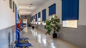 A hallway with blue chairs, potted plants, and a tiled floor. - Albergue Inturjoven Málaga - Hostel (Málaga)