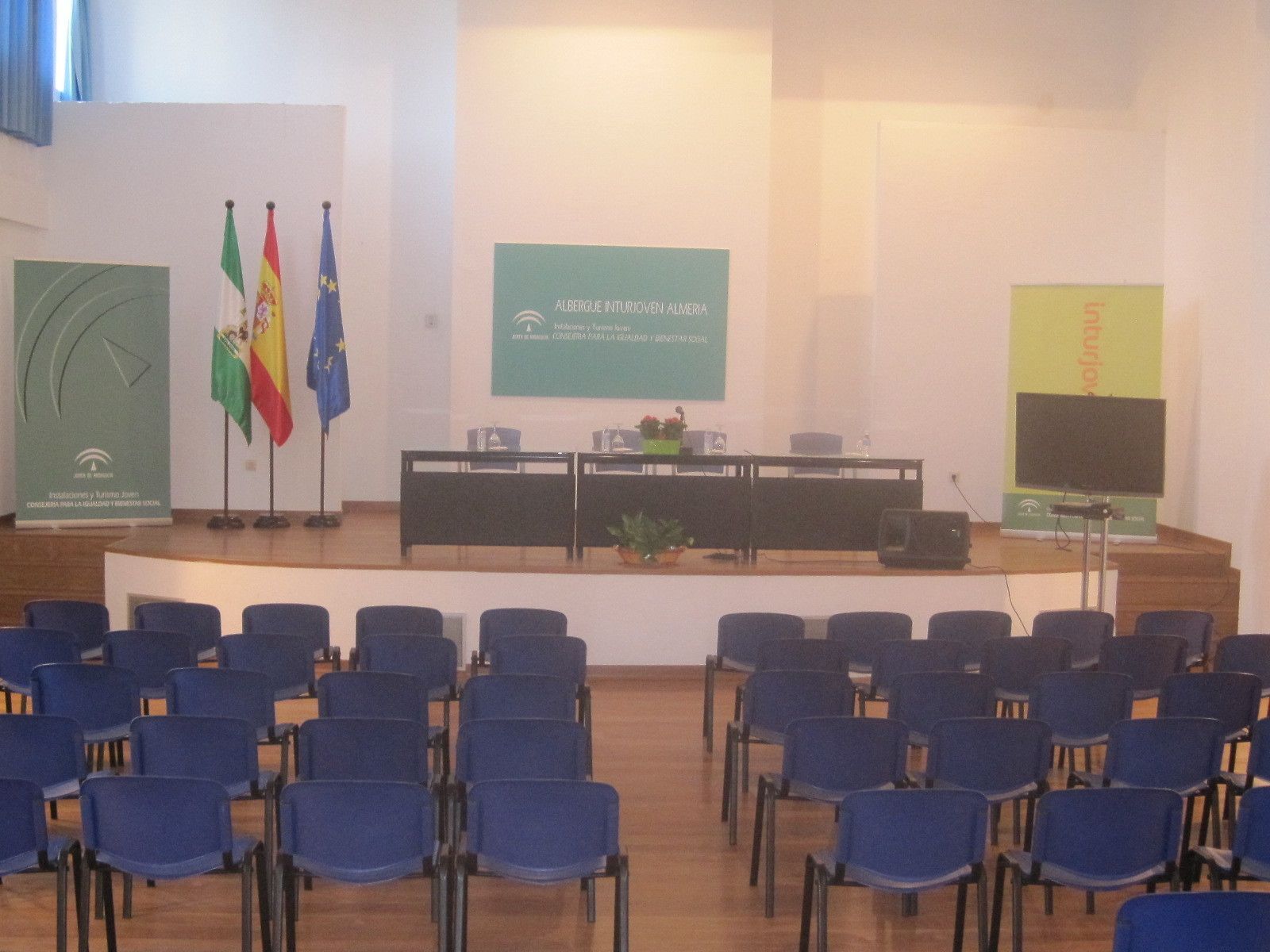 Ett konferensrum med en scen, stolar och flaggor.