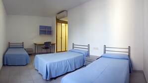 A dormitory room with three single beds, a desk, and a chair. - Albergue Inturjoven Almería - Hostel (Almeria)