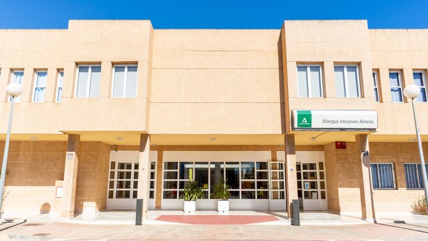 A building with a beige facade, multiple windows, and a sign indicating it is the Albergue Intervovem Almenda. - Albergue Inturjoven Almería - Hostel (Almeria)