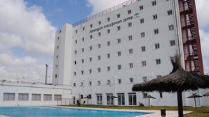 A hotel with a swimming pool, a white exterior, and a red balcony railing. - Albergue Inturjoven Jerez de la Frontera - Hostel (Jerez de la Frontera)