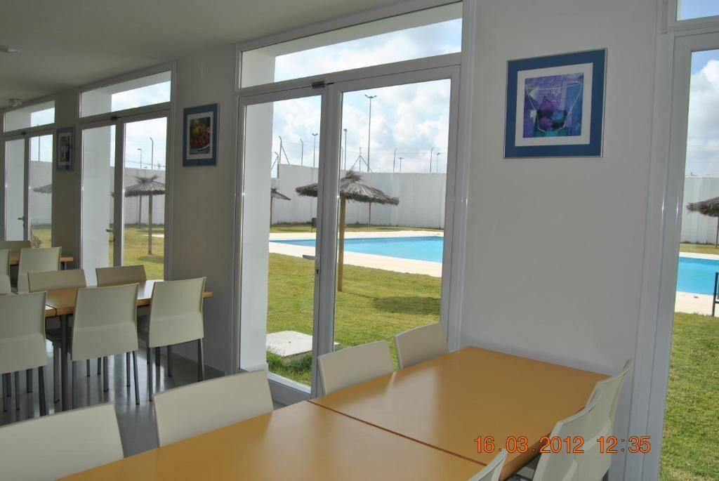 Un espace repas comprenant une table et des chaises, de grandes fenêtres et une vue sur une piscine.