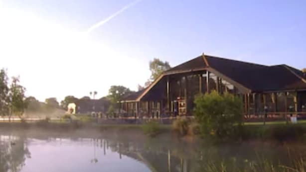 Un edificio grande con un espacio exterior techado cerca del agua.