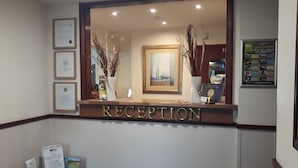 Un área de recepción con un certificado enmarcado en la pared, un cuadro enmarcado y un letrero que dice 