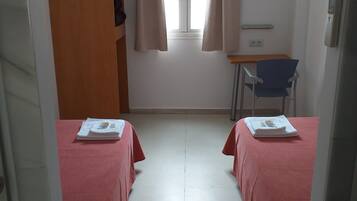 Een kamer met twee bedden, een bureau, een stoel, een kledingkast en een raam met gordijnen.