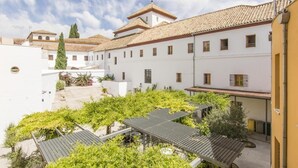 A courtyard with white buildings, a tiled roof, and greenery. - Albergue Inturjoven Córdoba - Hostel (Córdoba)