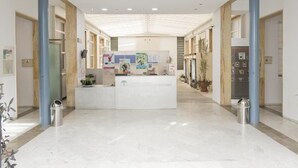 A reception area with a marble floor, a reception desk, and a large window. - Albergue Inturjoven Córdoba - Hostel (Córdoba)