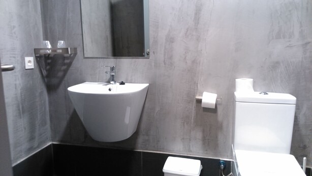 A modern bathroom with a white sink, a mirror, a toilet, and a black countertop. - Albergue Inturjoven Cazorla - Hostel (Cazorla)