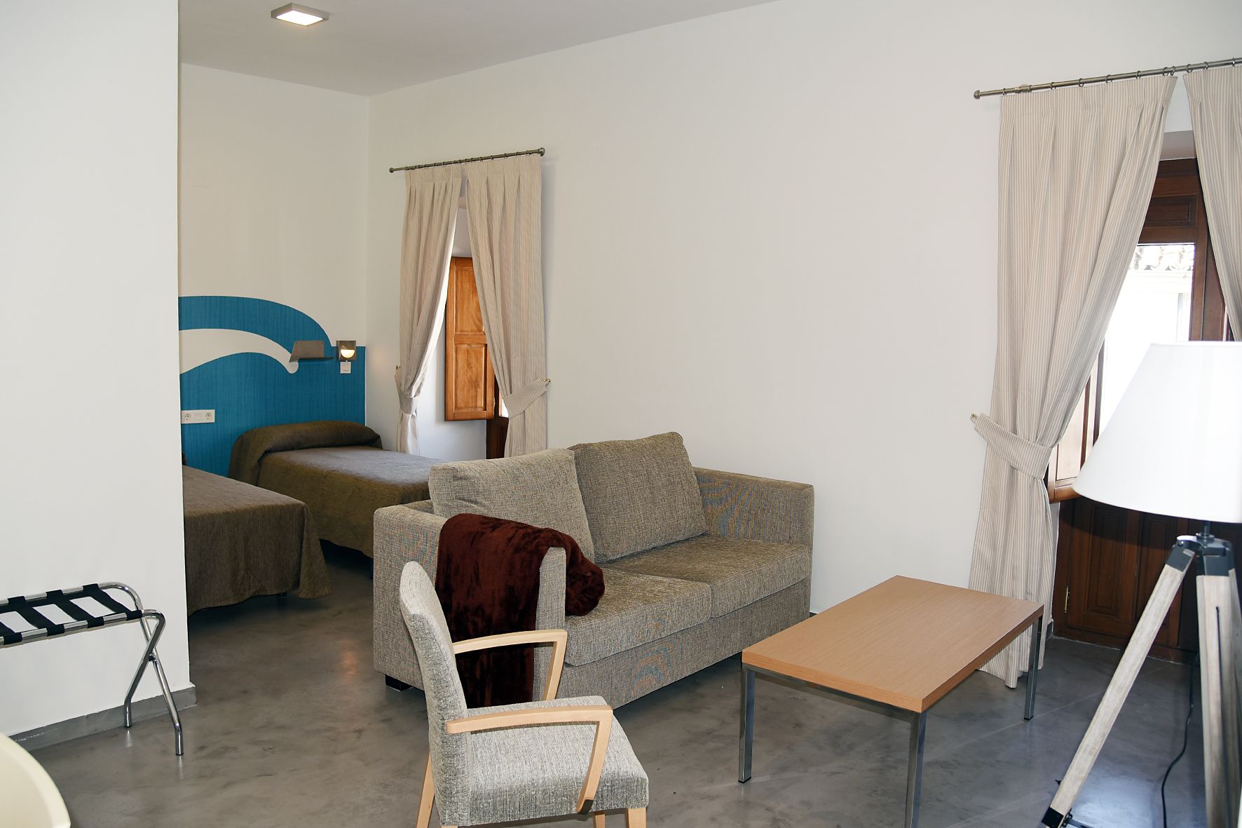 Een knus woongedeelte met een bank, een tafeltje, een stoel en een bed.
