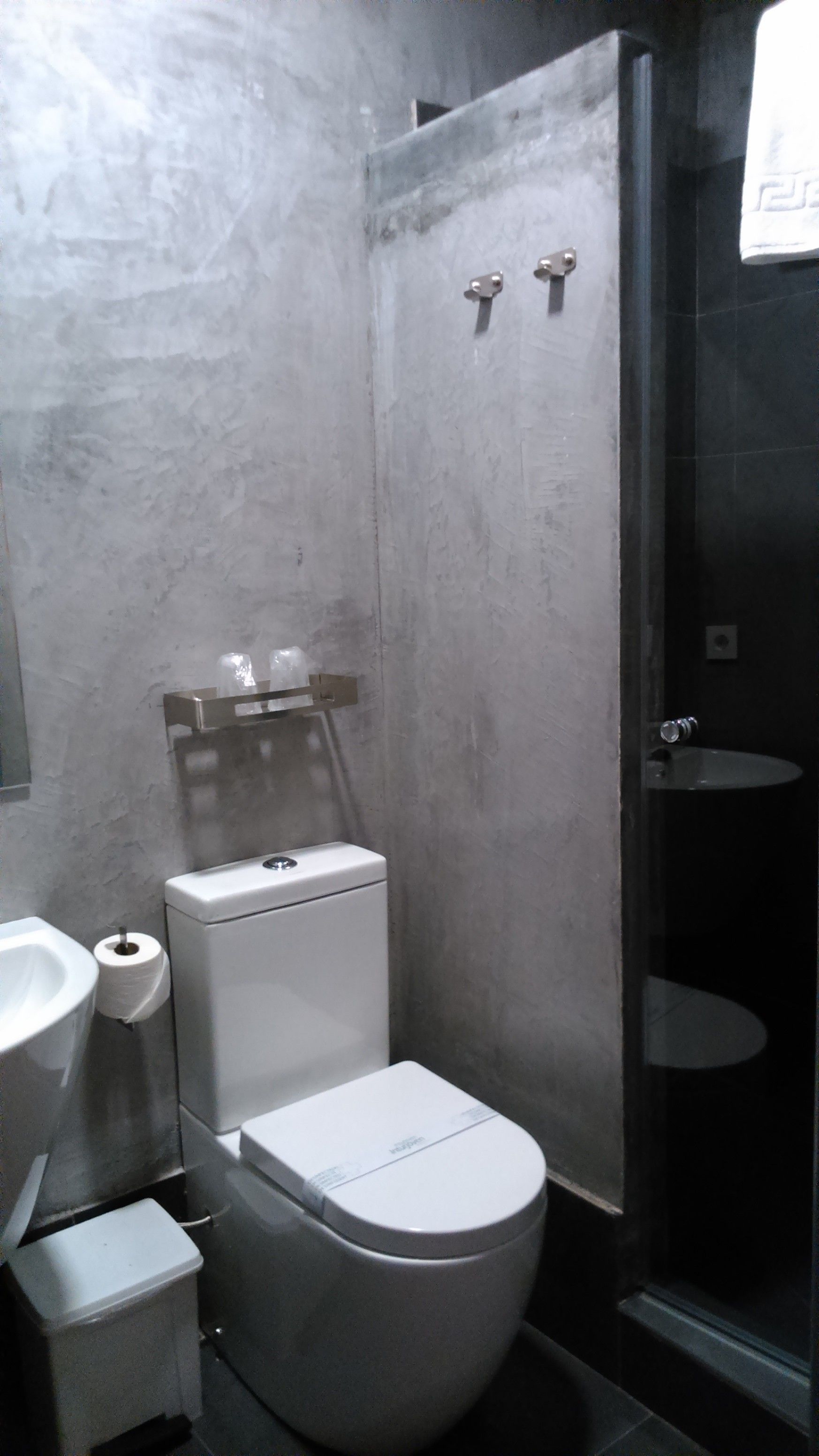 Un baño pequeño con inodoro, lavamanos y cabina de ducha.