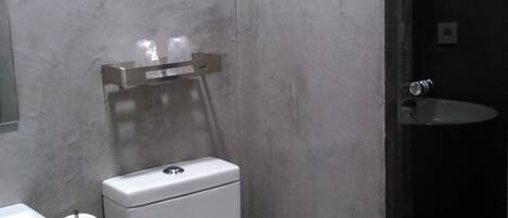 Un baño pequeño con inodoro, lavamanos y cabina de ducha.